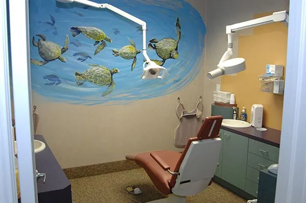 Playful ocean-themed murals on the wall of a child-friendly dental hygiene room